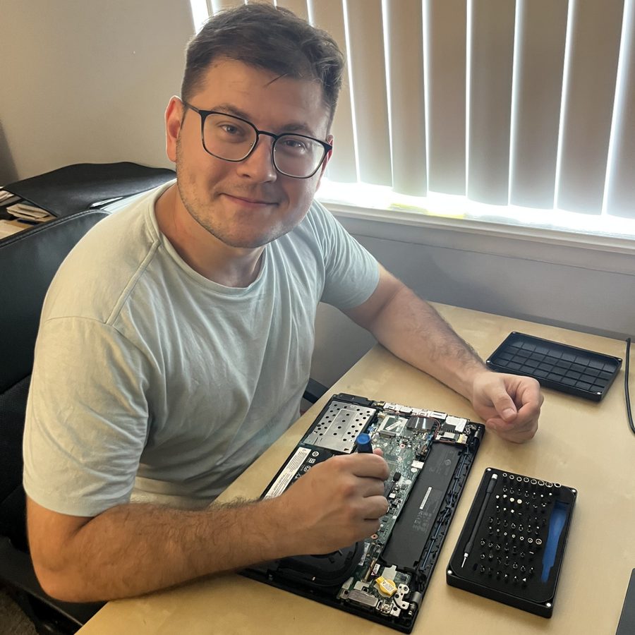 Vitaliy Maksymets repairing an opened laptop at his desk